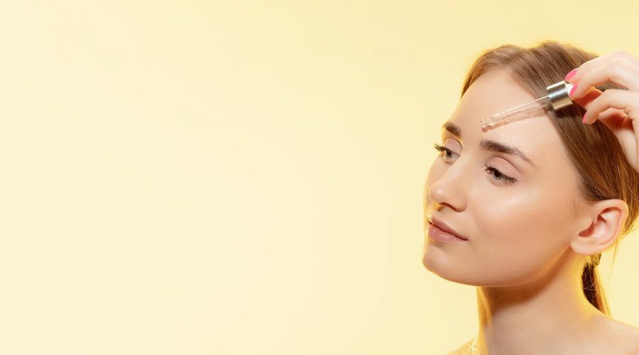 close-up-of-beautiful-young-woman-with-pouring-serum-oil-on-yellow (1)